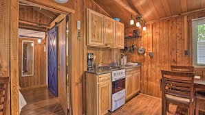 Interior de una cabaña de madera con cocina, que incluye estufa, horno y armarios.