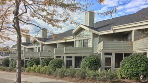 A row of townhouses with a central entrance, large windows, and a well-maintained front yard.