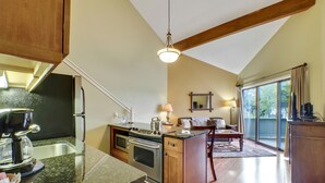 A kitchen with granite countertops, stainless steel appliances, and wooden cabinets. There is a dining area with a table and chairs, and a large window providing a view of the outdoors.
