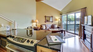 A kitchen with a stove, a dining table, and a sofa in the living area.