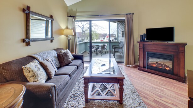 A living room with a sofa, a coffee table, a fireplace, and a television.