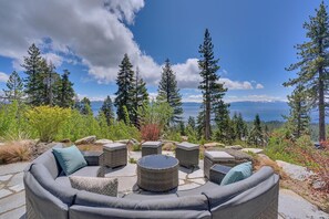 A patio with outdoor furniture, a stone pathway, and a view of a lake and mountains.