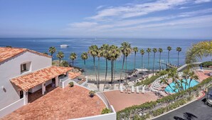 Un complexe hôtelier doté d’une piscine, de palmiers et offrant une vue sur l’océan.