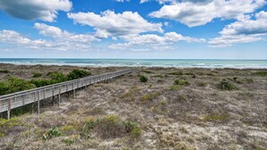 Un paisaje costero con un paseo de madera que conduce a la playa.