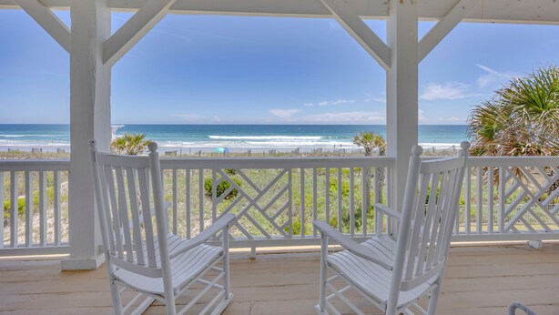 A covered porch with white railings and benches overlooking a beach. - Maultsby -Enjoy amazing ocean front views from this 10 bedroom home (Wrightsville Beach)