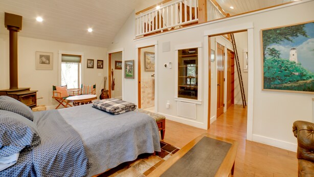 A spacious bedroom with a large bed, a wooden ceiling, and a balcony. - Pool Access: Pet-Friendly Pennsylvania Cabin! (Laughlintown)