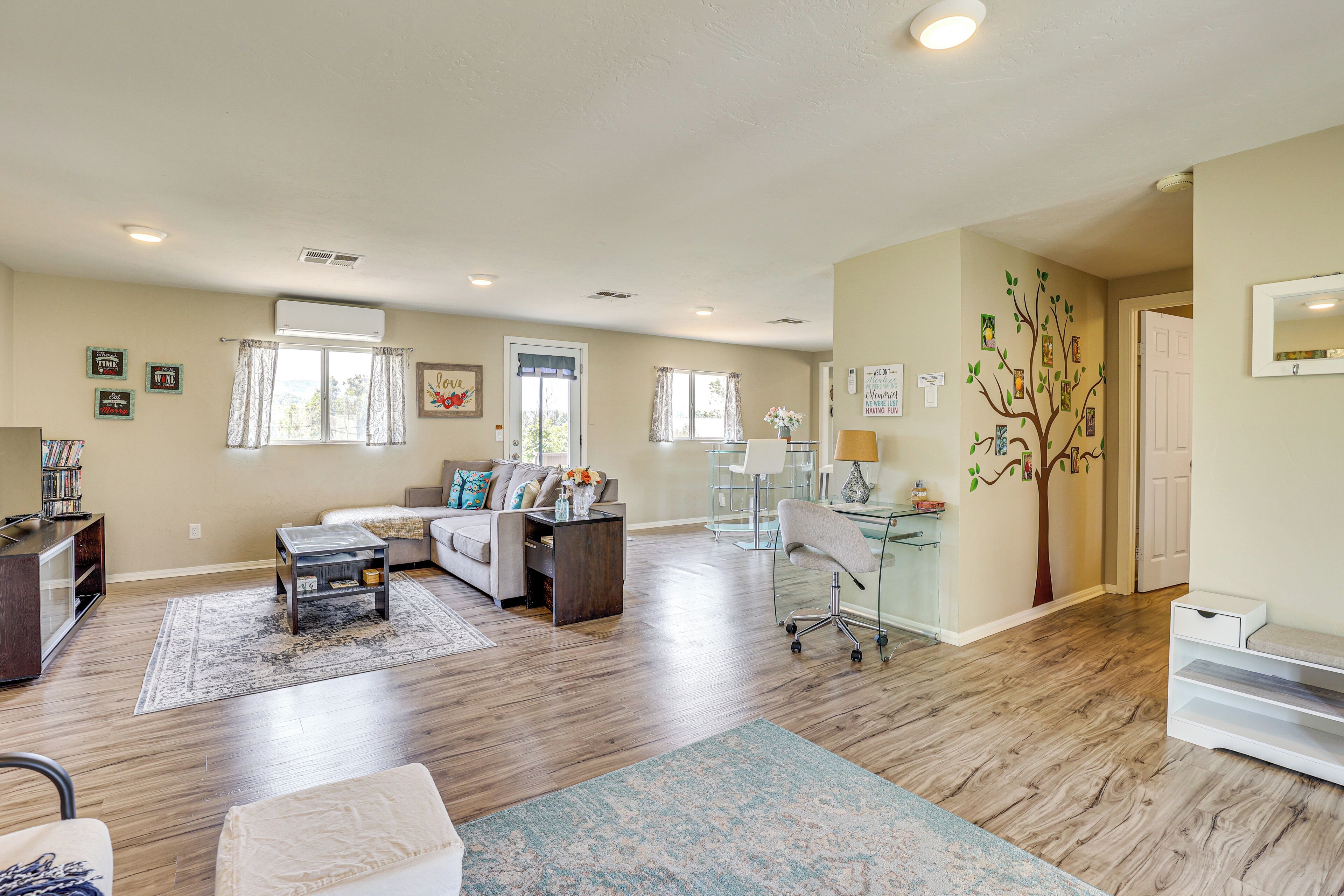 A spacious living room with hardwood floors, a sofa, a coffee table, and a desk with a chair.