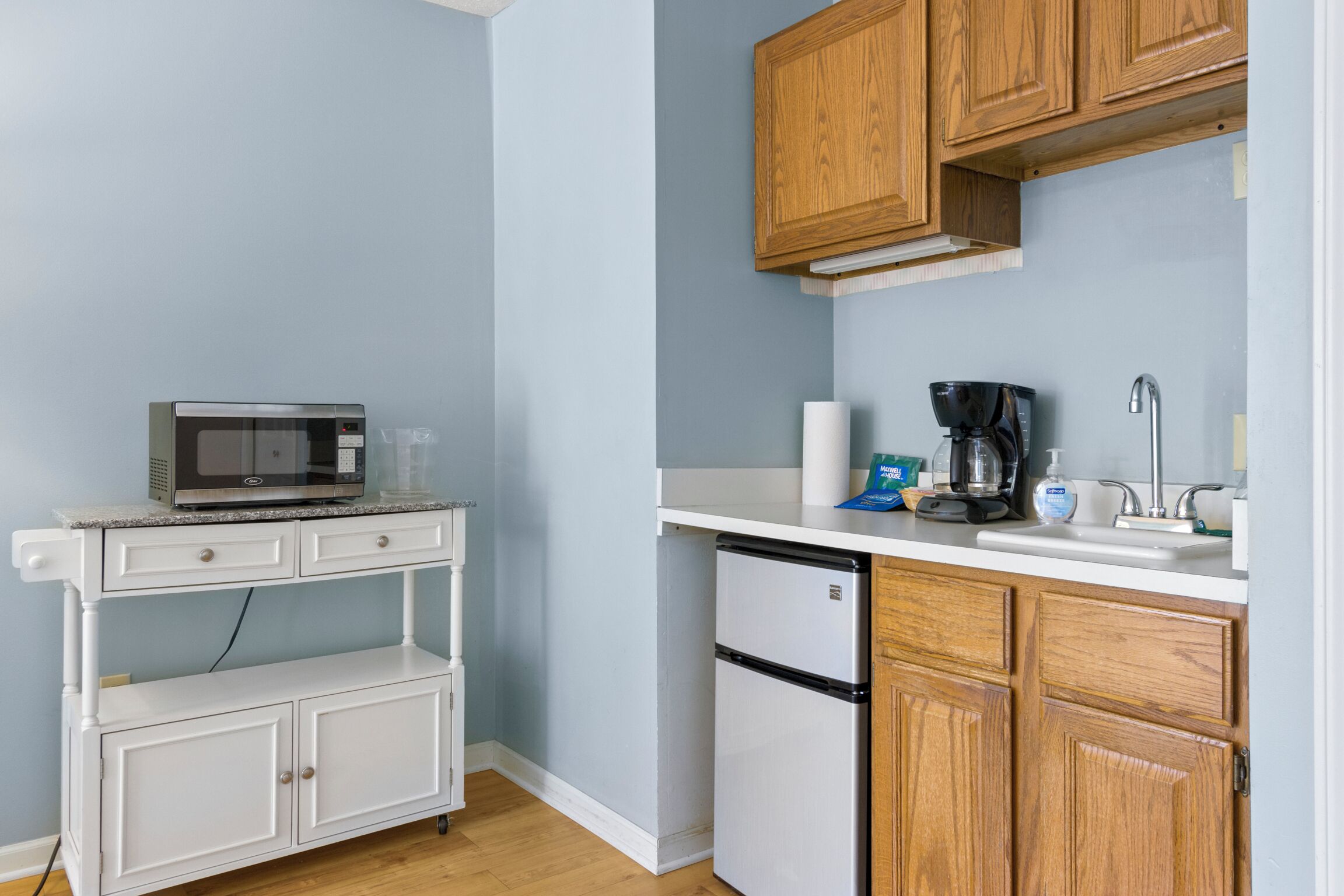 A compact kitchen with a microwave, coffee maker, and refrigerator.