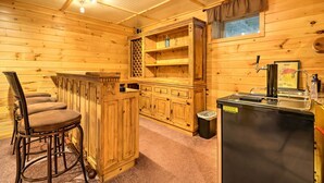 L’intérieur d’un chalet en bois comprend un bar, des sièges et un évier.