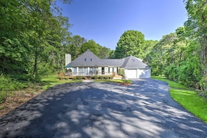 Stroll up the covered porch to the two-story house surrounded by lush greenery and mature trees.