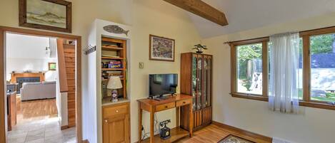 A spacious living area with a wooden desk, television, and a large window with curtains.