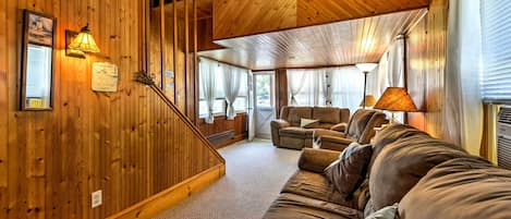 A wooden interior with a sofa, a lamp, and a staircase.