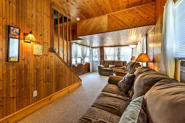 A wooden interior with a sofa, a lamp, and a staircase.