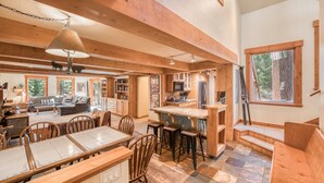 Une cuisine spacieuse avec des poutres en bois, un coin repas avec une grande table et des chaises, et un salon confortable avec un canapé et une cheminée.