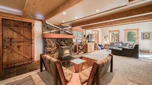 Un salon chaleureux avec une cheminée en pierre, des meubles en bois et une grande porte en bois.