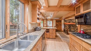 Une cuisine moderne avec des armoires en bois, des comptoirs en granit, une cuisinière intégrée et une grande fenêtre qui laisse entrer la lumière naturelle.