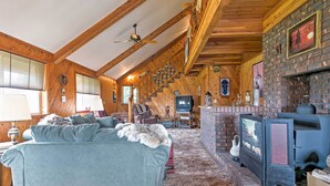 Una sala de estar acogedora con chimenea, paredes de madera, una escalera y un televisor.
