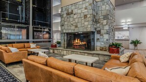 A modern lobby with a stone fireplace, leather sofas, and a glass coffee table. - ML 345: Ski-In/Out | Slope Views | Sleeps 6 | Steps to Ballhooter (Snowshoe)