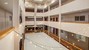 A multi-level atrium with a central open space, wooden railings, and string lights. - ML 345: Ski-In/Out | Slope Views | Sleeps 6 | Steps to Ballhooter (Snowshoe)