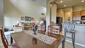 A dining area with a wooden table, chairs, and a patterned runner. There is a kitchen in the background with wooden cabinets and a microwave. - Golf Course View & Pool Access: Gold Canyon Gem (Gold Canyon)