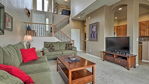 A spacious living room with a staircase, a large flat-screen TV, and a cozy seating area. - Golf Course View & Pool Access: Gold Canyon Gem (Gold Canyon)