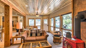Un salon chaleureux avec une cheminée, un plafond en bois et de grandes fenêtres.