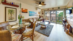 A living room with wicker furniture, a glass coffee table, and a ceiling fan. - Pristine Lihue Condo w/ Balcony: Walk to Beach! (Lihue)