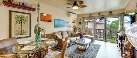 A living room with wicker furniture, a glass coffee table, and a ceiling fan.