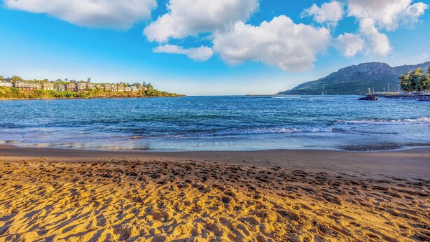 A beach with clear skies and a mountain in the background. - Pristine Lihue Condo w/ Balcony: Walk to Beach! (Lihue)
