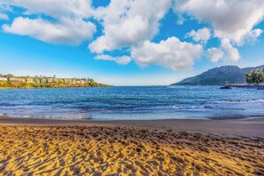 Una playa con cielos despejados y una montaña al fondo.