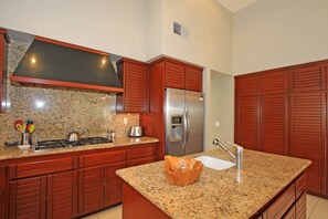 A kitchen with granite countertops, stainless steel appliances, and wooden cabinetry. - Golf course-view 2BR condo in PGA West with pool, patio, and fireplace. (La Quinta)