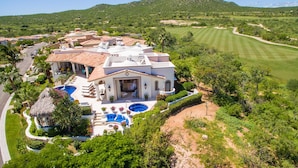 A large, white villa with multiple rooms and a swimming pool, surrounded by lush greenery and a golf course. - Luxury Cabo del Sol Villa w/ Cook, Infinity Pool, Hot Tub, Firepit, & Golf Views (Turistico Corredor)