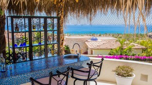 A bar area with a mosaic countertop, two bar stools, a potted plant, and a view of the ocean. - Luxury Cabo del Sol Villa w/ Cook, Infinity Pool, Hot Tub, Firepit, & Golf Views (Turistico Corredor)