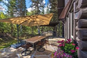 A patio with a table and chairs, an umbrella, and a stone floor.