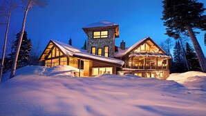 A large, stone cabin with a prominent tower and multiple windows, surrounded by snow and trees. - ALPEN RIDGE- Elevated Luxury Estate with Slopeside Views and Access (Mountain Village)
