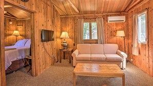 A wooden cabin interior with a bed, sofa, and a coffee table. - 1/2 Mi to Dtwn! Suttons Bay Cottage w/ Fire Pit (Suttons Bay)