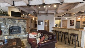 Una sala de estar acogedora con chimenea de piedra, sofá de cuero y taburetes de madera.