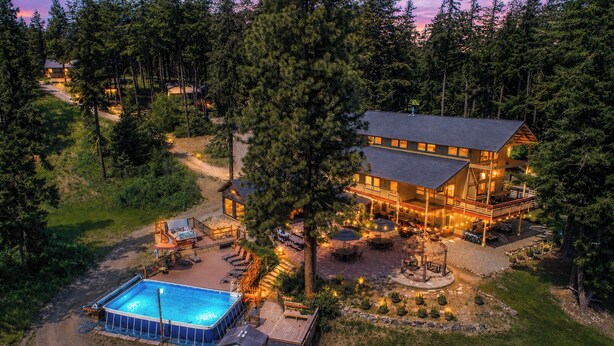 A large lodge with a swimming pool, outdoor seating, and a hot tub.