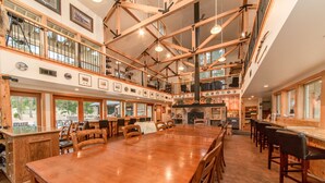 A spacious, multi-level restaurant with a large wooden dining table, multiple seating areas, and a fireplace.