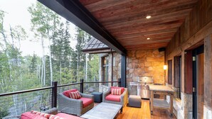A wooden deck with wicker furniture and a stone wall.