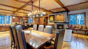 A spacious dining area with a wooden table and chairs, a fireplace, and a stone fireplace surround.
