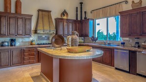 A kitchen with wooden cabinets, a central island, and a window with a view.