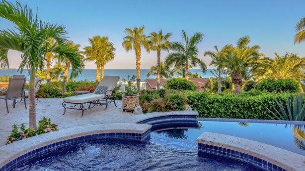 A pool area with lounge chairs and a view of the sea.