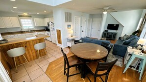 A modern kitchen with white cabinets, a wooden dining table, and a bar area. - KD108- Near the Beach- 4 BRs, Just a Short Stroll to the Beach, Dog Friendly! (Kill Devil Hills)