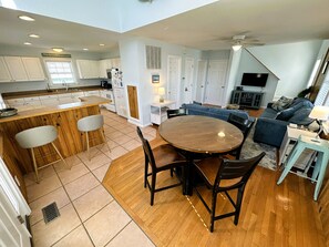 A modern kitchen with white cabinets, a wooden dining table, and a bar area.