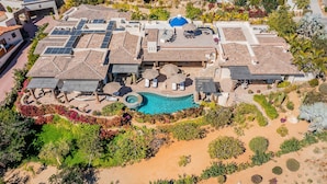 An aerial view of a resort with multiple buildings, a swimming pool, and landscaped gardens.