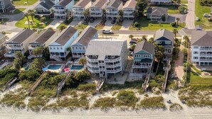 Eine Küstenwohngegend mit Strandhäusern, darunter ein Mehrstöckiger Neubau mit Balkonen und einem Pool.