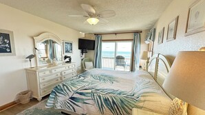 A bedroom with a bed, dresser, and a ceiling fan. There is a view of the ocean through the window. - SN9241- Beautiful Oceanfront Home with Great Ocean Views and Dog Friendly! (Nags Head)