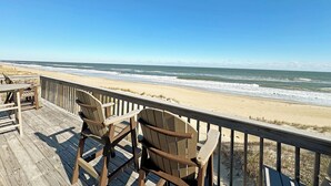 A wooden deck with two wooden chairs facing a beach. - SN9241- Beautiful Oceanfront Home with Great Ocean Views and Dog Friendly! (Nags Head)