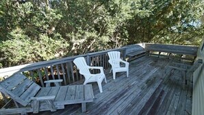 Una terraza de madera con dos sillas Adirondack blancas y una mesita.